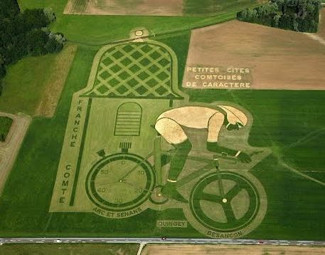 Luftbild: Landwirtschaftsfahrzeuge formen ein Velo auf einer Wiese